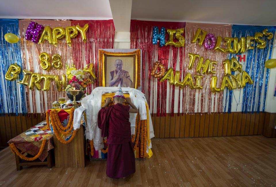 A young monk offers a ceremonial scarf in front of a portrait of his spiritual leader the Dalai Lama during his 88th birthday celebration in Kathmandu, Nepal, Thursday, July 6, 2023. (AP Photo/Niranjan Shrestha)