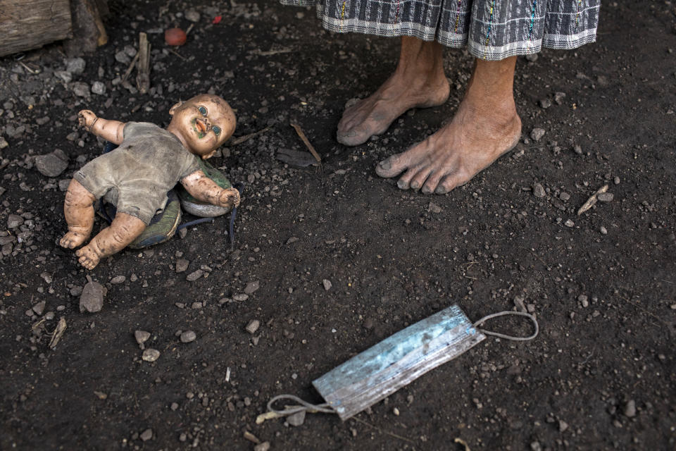 Felisa Lem Cal, 68, stands outside her house next to a doll and a discarded protective face mask, in the makeshift settlement Nuevo Queja, Guatemala, Tuesday, July 6, 2021. The government of Guatemala has not been much help to the residents of the new settlement, declaring it uninhabitable. (AP Photo/Rodrigo Abd)