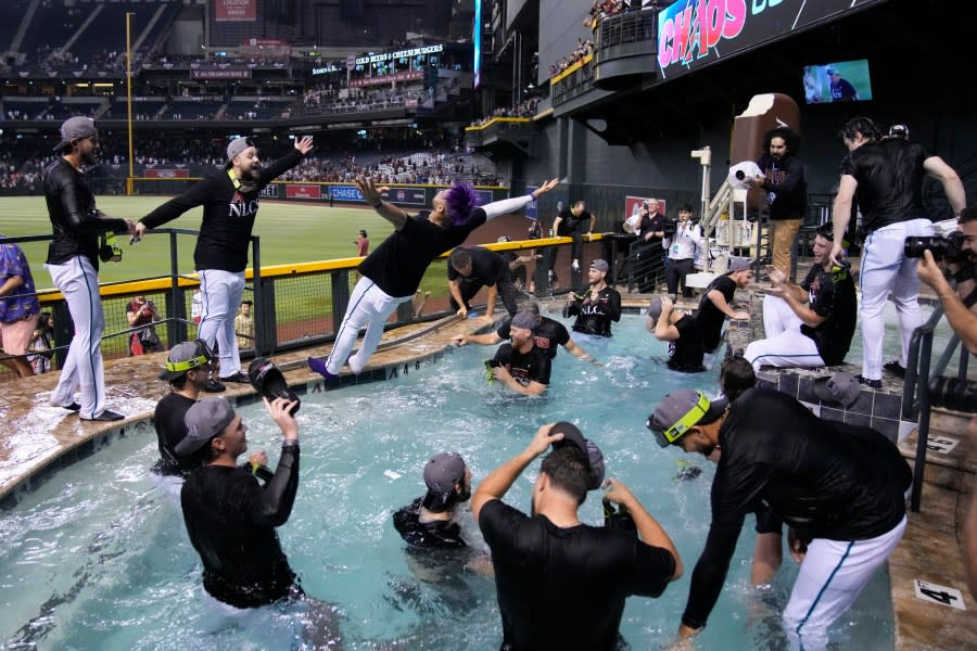 Arizona Diamondbacks left fielder Lourdes Gurriel Jr., center, falls into the pool after the Diamondbacks defeated the Los Angeles Dodgers 4-2 in Game 3 to win a baseball NL Division Series, Wednesday, Oct. 11, 2023, in Phoenix. (AP Photo/Rick Scuteri)