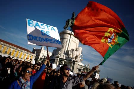 A woman holds a poster saying "enough incompetence" during a demonstration in a tribute to the victims of the deadly fires in Portugal, in Praca do Comercio square, downtown Lisbon, Portugal October 21, 2017. REUTERS/Pedro Nunes