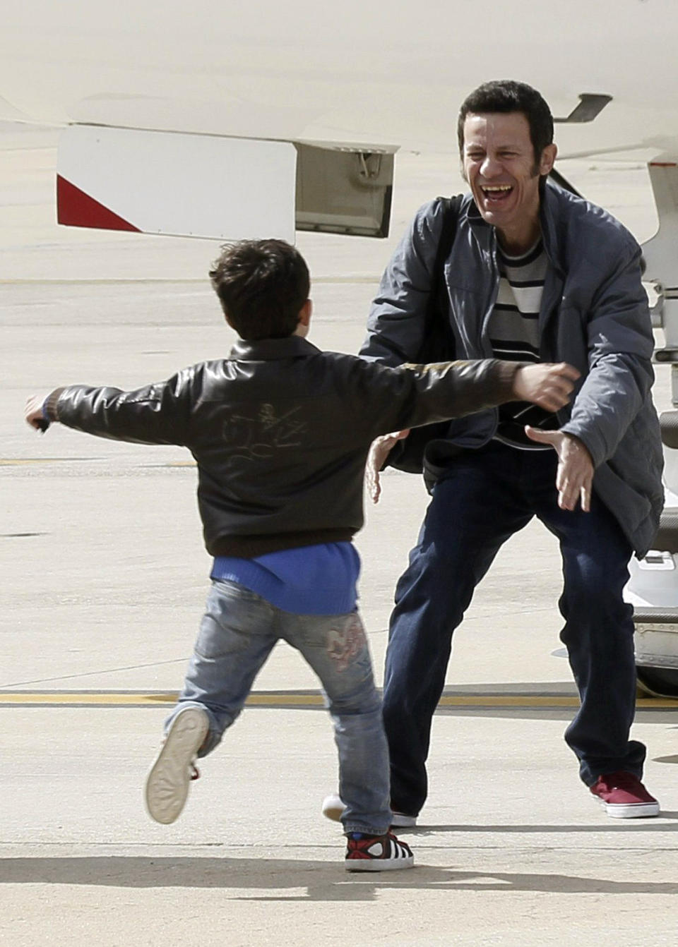 Spanish reporter Javier Espinosa, reacts as his soon Yerai runs towards him upon his arrival at the military airport of Torrejon in Madrid, Spain, Sunday, March 30, 2014. Two Spanish journalists who were freed after being kidnapped for more than six months in Syria by a rogue al-Qaida group are flying back home Sunday, Spain’s Defense Ministry said. The El Mundo newspaper reported earlier that its war correspondent Javier Espinosa made contact late Saturday from Turkey, where he and photographer Ricardo Garcia Vilanova were under military protection. (AP Photo/Paco Campos, Pool)