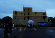 Mourners stand outside the Kyoto Animation building which was torched by arson attack, in Kyoto