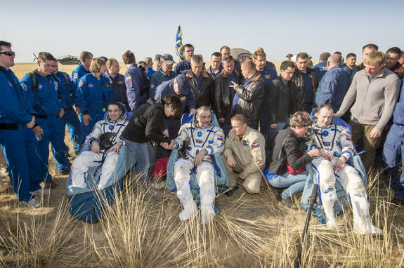 Expedition 36 Flight Engineer Chris Cassidy of NASA, left, Commander Pavel Vinogradov of the Russian Federal Space Agency (Roscosmos), center, and, Flight Engineer Alexander Misurkin of Roscosmos, sit in chairs outside the Soyuz TMA-08M capsule