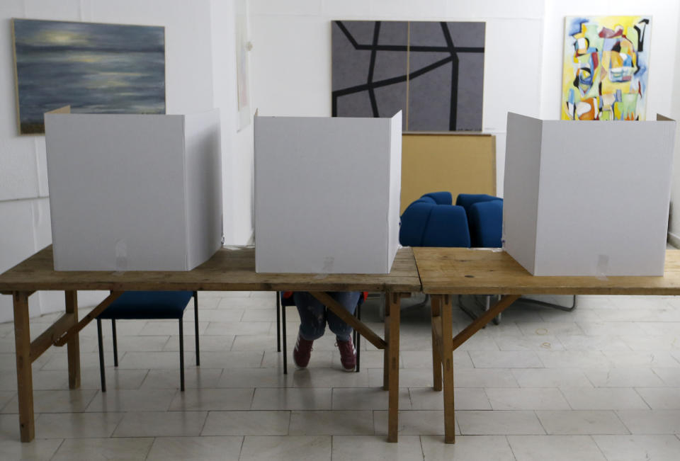 A woman prepares her ballot for a general election at a poling station in the Bosnian town of Laktasi, northwest of Sarajevo, Bosnia, Sunday, Oct. 7, 2018. Sunday's vote is seen as a test of whether Bosnia will move toward integration in the European Union and NATO or remain entrenched in war-era rivalries. (AP Photo/Darko Vojinovic)