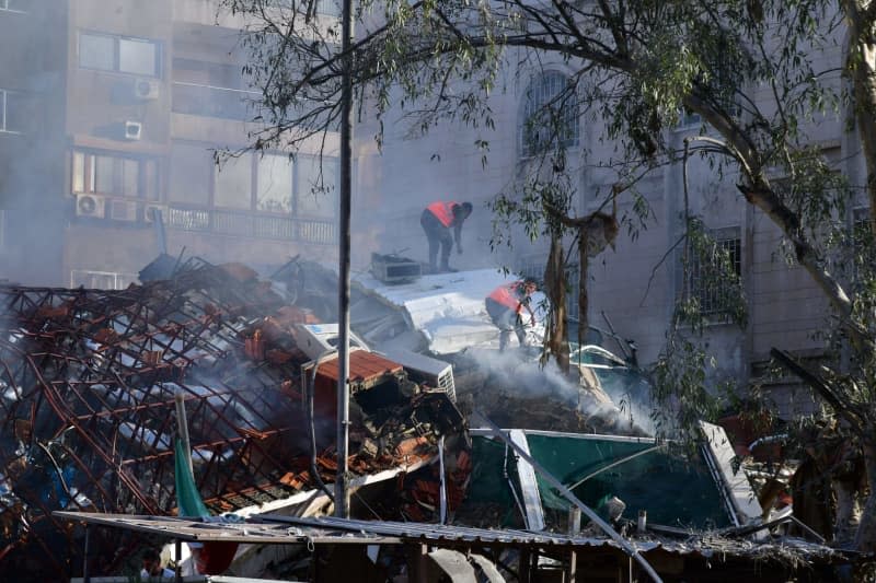 A photo released by the official Syrian Arab news agency (SANA) on 01 April shows people gathering around an Iranian diplomatic destroyed building after a suspected Israeli airstrike. -/SANA/dpa