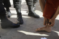 Theary Seng, a Cambodian-American lawyer, dressed in a prison-style orange outfit, takes off Khmer Rouge-era ankle shackles before enering Phnom Penh Municipal Court in Phnom Penh, Cambodia, Tuesday, Jan. 4, 2022. Cambodian security forces on Tuesday briefly detained Theary, a prominent rights activist, as she walked barefoot near the prime minister’s residence in Phnom Penh, wearing the orange outfit and the shackles. She was released, shortly afterwards, and arrived at the Phnom Penh court for the resumption of her trial on treason charges. (AP Photo/Heng Sinith)