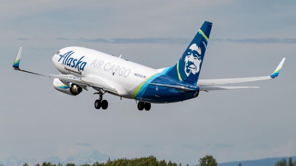 A blue-tailed Alaska Air Cargo jet takes off, viewed from the rear.