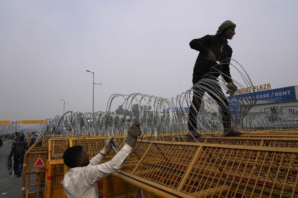 Workers put up barbed wire on top of barricades on a major highway at Singhu near New Delhi to stop thousands of protesting farmers from entering the capital, India, Tuesday, Feb.13, 2024. Farmers, who began their march from northern Haryana and Punjab states, are asking for a guaranteed minimum support price for all farm produce. (AP Photo/Manish Swarup)