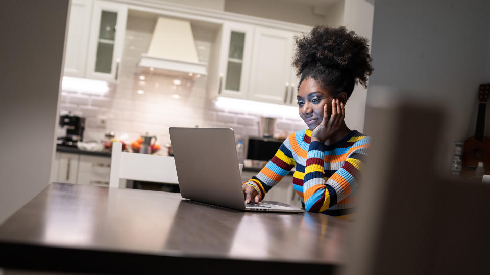 African Woman using laptop at home at night.