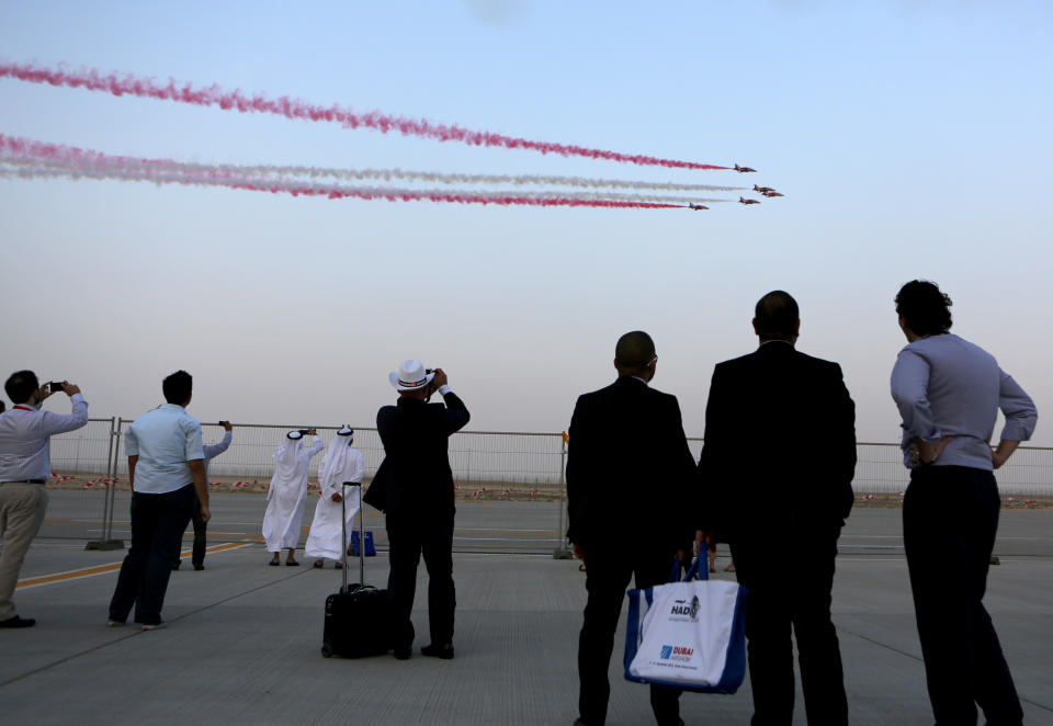 Emirati and foreign visitors take photos of Al Fursan, the aerobatics demonstration team of the UAE Air Force during the Dubai Airshow in Dubai, United Arab Emirates, Monday Nov. 18, 2013. (AP Photo/Kamran Jebreili)