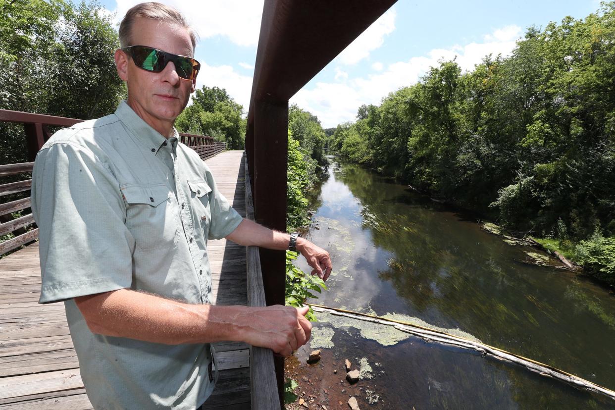 Matthew Gudorf, president and COO of Eco-Maxx, looks over a boom in the Tuscarawas River from on a bridge on Ohio & Erie Canal Towpath Trail near Wolf Creek Trailhead in Barberton.