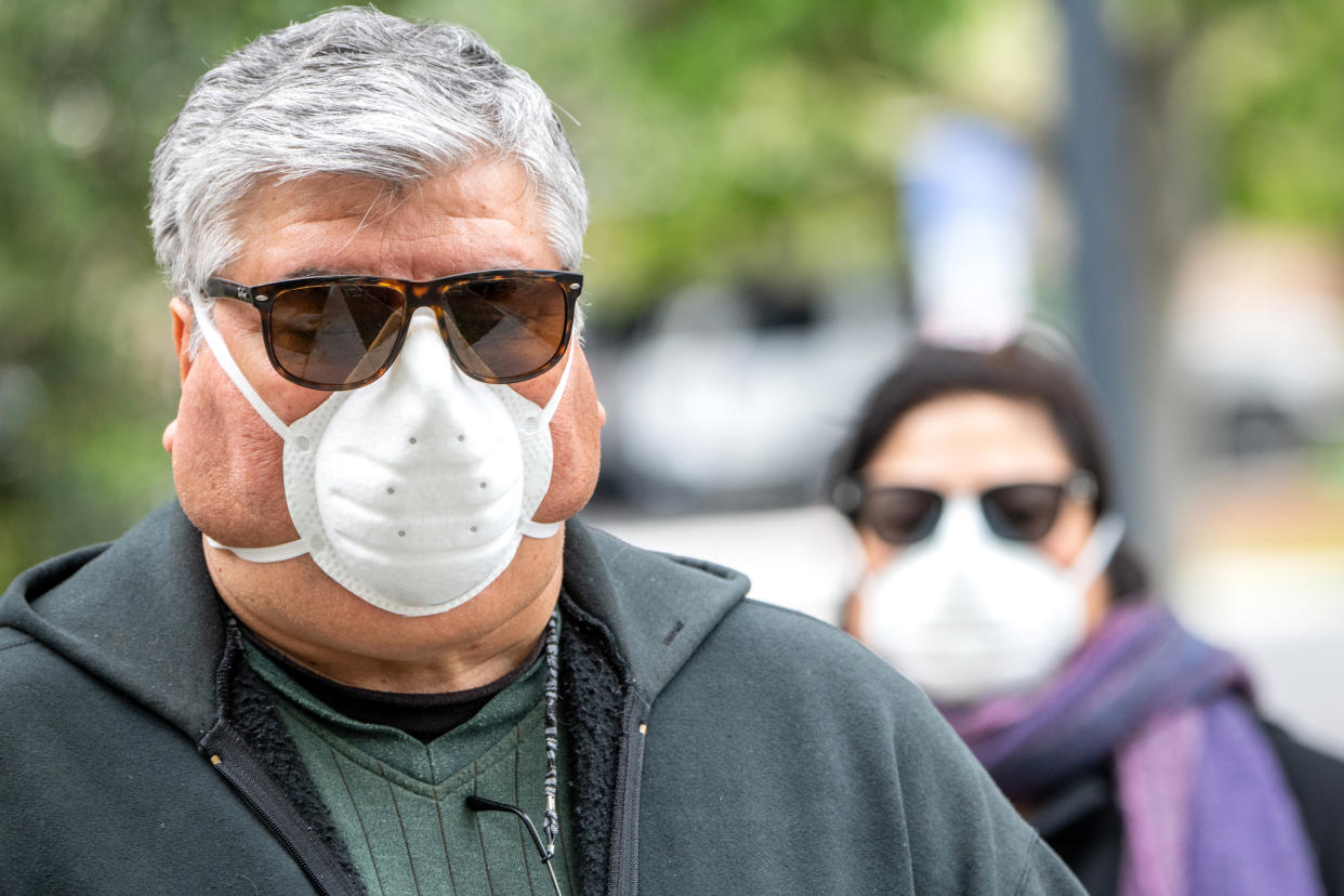 Overweight hispanic or middle eastern senior couple wearing a N95 protective mask due Covid-19 pandemic