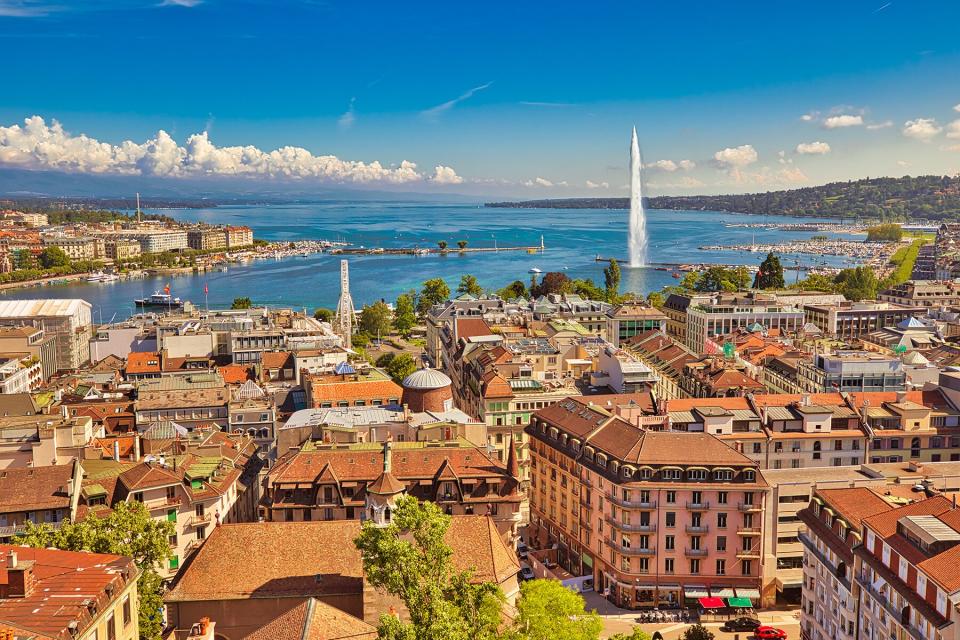 Geneva skyline cityscape, French-Swiss in Switzerland. Aerial view of Jet d'eau fountain, Lake Leman, bay and harbor from the bell tower of Saint-Pierre Cathedral