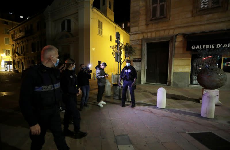 FILE PHOTO: Police officers check a person in Nice as the French Riviera city prepares for a new nightly curfew imposed in an effort to combat the the coronavirus