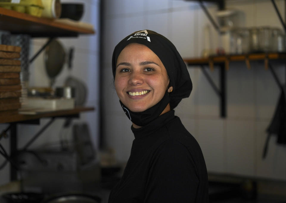 Flor Peña, from Venezuela, poses for a photo at her work place in a Venezuelan cuisine restaurant in Mexico City, Tuesday, Feb. 21, 2023. The industrial safety engineer said she and her firefighter husband left Caracas with their two young children in 2017 after seeing her father die of a heart attack when four overcrowded public hospitals refused to treat him (AP Photo/Fernando Llano)