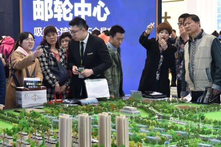 Sales staff introduce models of a residential compound to visitors during Dalian Spring Real Estate Fair in Dalian