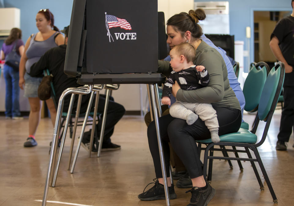 Miranda Padilla holds her 11-month-old son Grayson Sanchez while marking her ballot at a polling center in the South Valley area of Albuquerque, N.M., Tuesday, Nov. 8, 2022 (AP Photo/Andres Leighton)