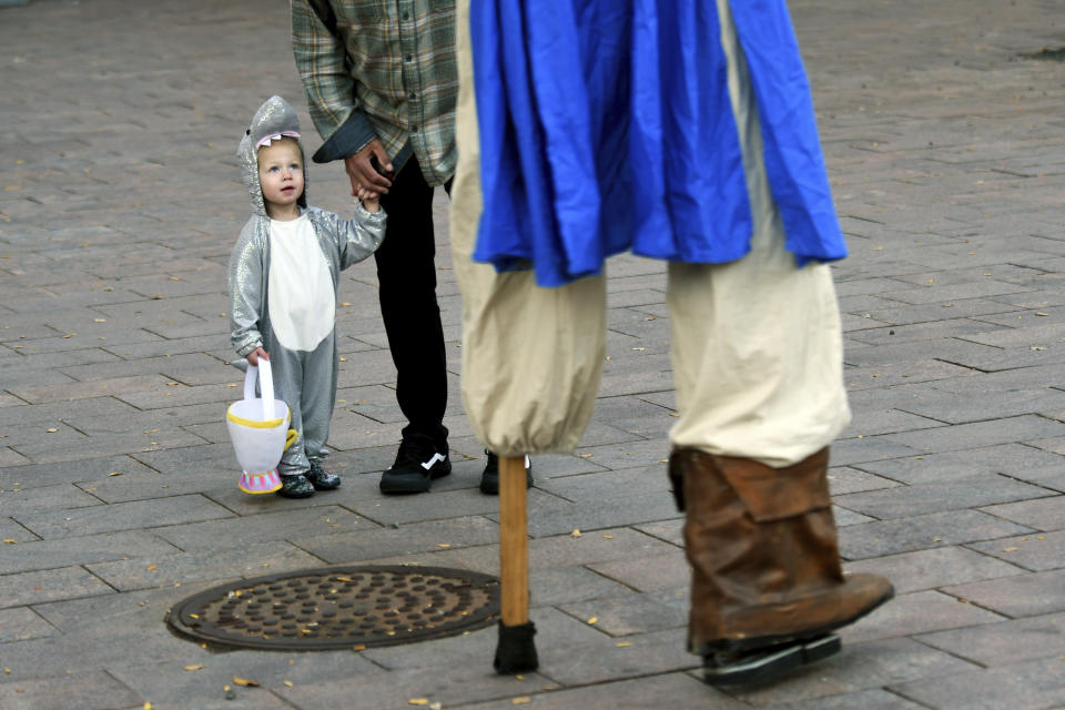 Stella, 2, looks up at a peg-legged pirate on stilts during a Halloween celebration at Denver's Union Station on Thursday, Oct. 28, 2021. Though the pandemic remains a concern, top health officials are largely giving outside activities like trick-or-treating the thumbs up. (AP Photo/Thomas Peipert)