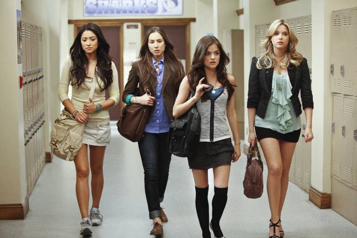 The cast of "Pretty Little Liars" walking down a school hallway