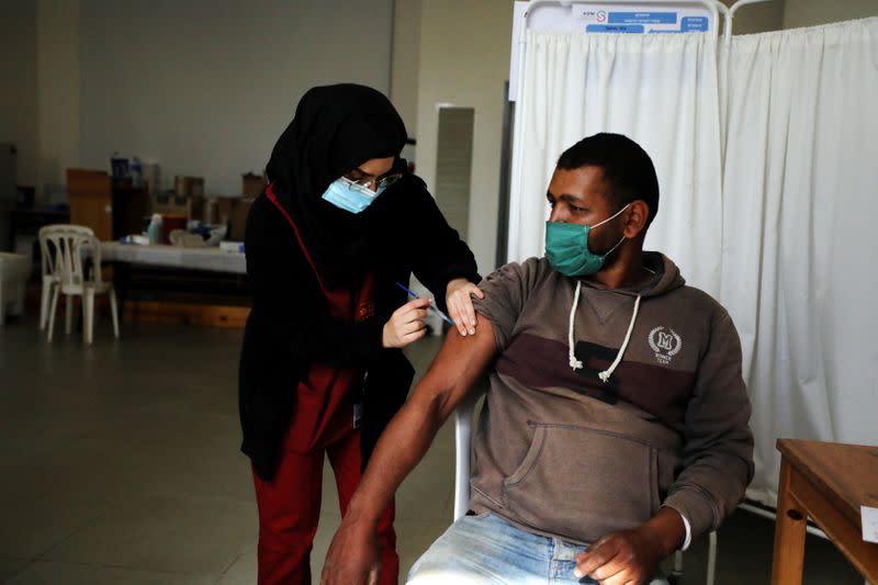 A Palestinian labourer who works within Israel or its settlements in the occupied West Bank, is vaccinated at an Israeli facility at Shaar Efraim crossing from Israel to the West Bank