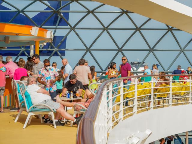People on the top deck of Wonder of the Seas enjoy drinks at the bar