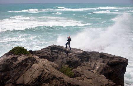 A man takes photos while standing on a cliff on the island's south shore battered by winds from approaching Hurricane Gonzalo, in Astwood Park, October 17, 2014. REUTERS/Nicola Muirhead