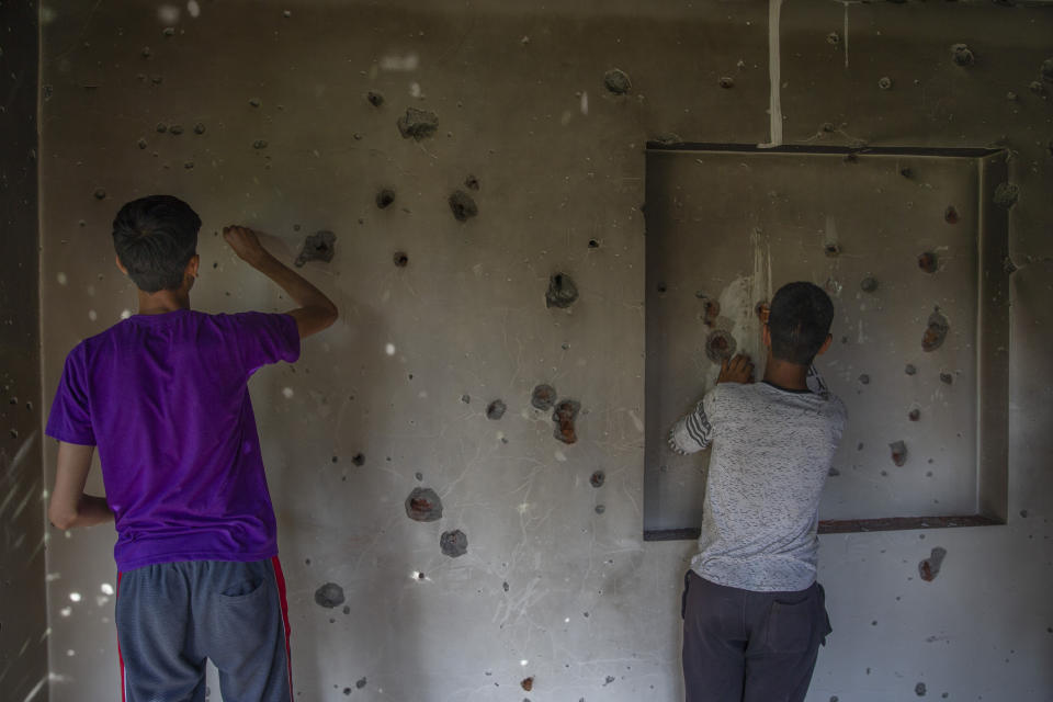 Kashmiri boys try to take out bullets from the wall of a damaged house after a gun battle in the outskirts of Srinagar, Indian controlled Kashmir, Tuesday, June 29, 2021. Hours after arresting a rebel commander, police Tuesday said he was killed during a crossfire with another militant in the disputed city's region's main city. (AP Photo/Dar Yasin)