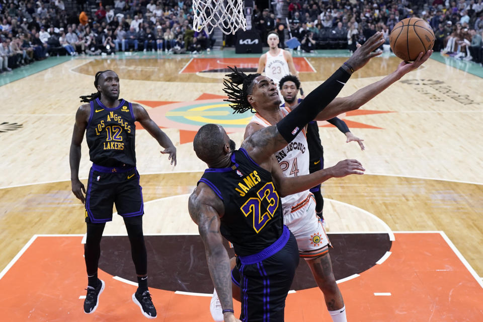 San Antonio Spurs guard Devin Vassell (24) drives to the basket against Los Angeles Lakers forward LeBron James (23) during the second half of an NBA basketball game in San Antonio, Friday, Dec. 15, 2023. (AP Photo/Eric Gay)