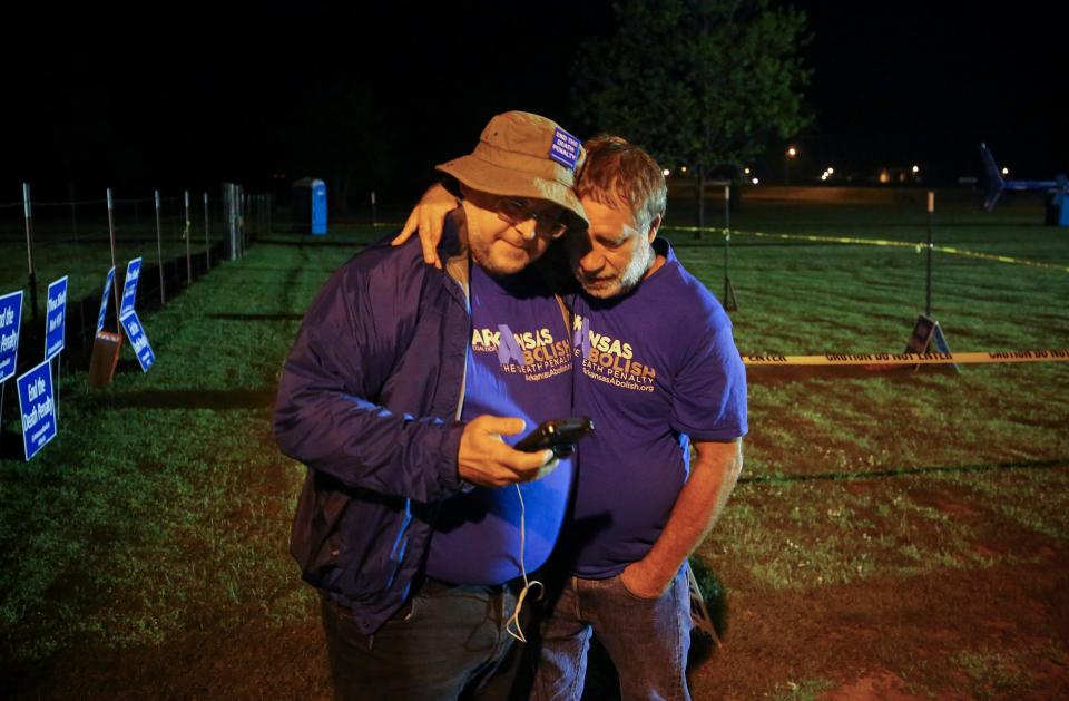 Anti-death penalty supporter Randy Gardner, right, embraces Abraham Bonowitz, left, after they read on his phone the 11:45 p.m., decision to halt the execution in their taped off "protest corral"  - Credit: AP