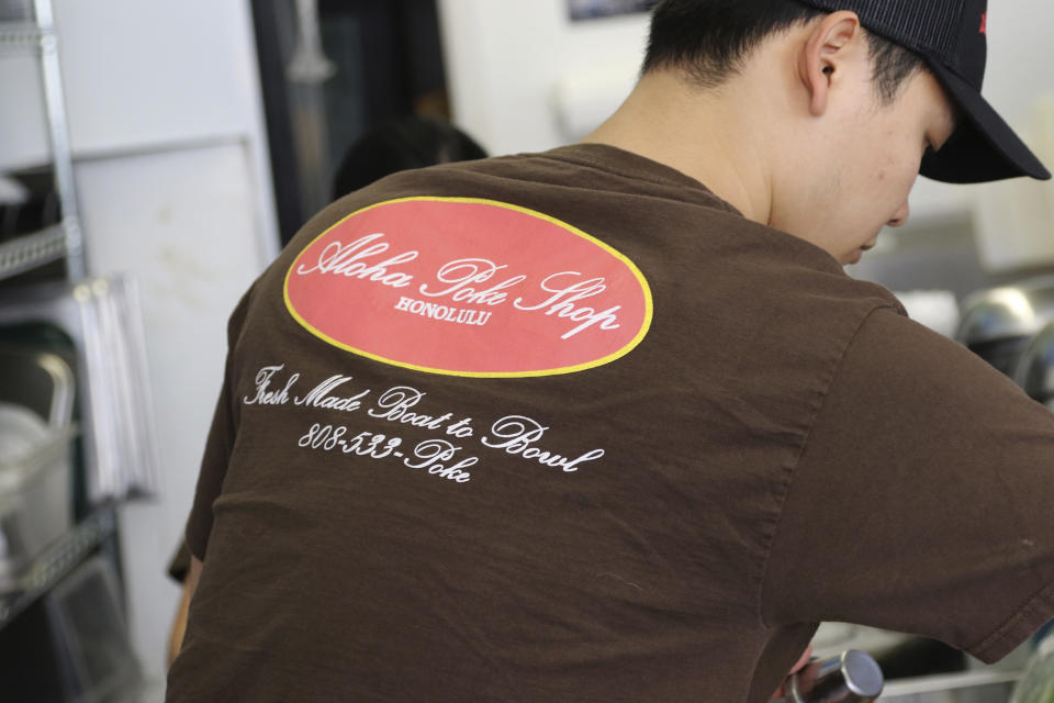 This Tuesday, April 16, 2019, photo shows Ryne Aniya preparing food before the lunch rush at Aloha Poke Shop, a store in Honolulu that received a letter from Chicago-based Aloha Poke Co. saying the Illinois company had trademarked "Aloha Poke" and the Hawaii company would need to change its name. Hawaii lawmakers are considering adopting a resolution calling for the creation of legal protections for Native Hawaiian cultural intellectual property. (AP Photo/Audrey McAvoy)