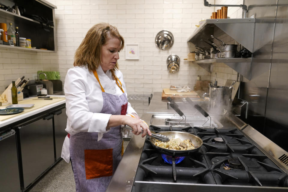 Amy Brandwein, chef and owner of Centrolina, prepares a dish in her restaurant kitchen, Thursday, Dec. 16, 2021, in Washington. While restaurants in the U.S. and United Kingdom are open without restrictions and often bustling, they are entering their second winter of the coronavirus pandemic anxious about what’s ahead. (AP Photo/Patrick Semansky)