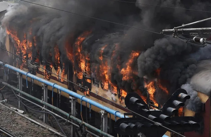 Smoke billows out from a passenger train coach after it was set on fire by protestors during a protest against the ‘Agnipath’ reforms for recruiting personnel for armed forces in Secunderabad city on 17 June (Reuters)