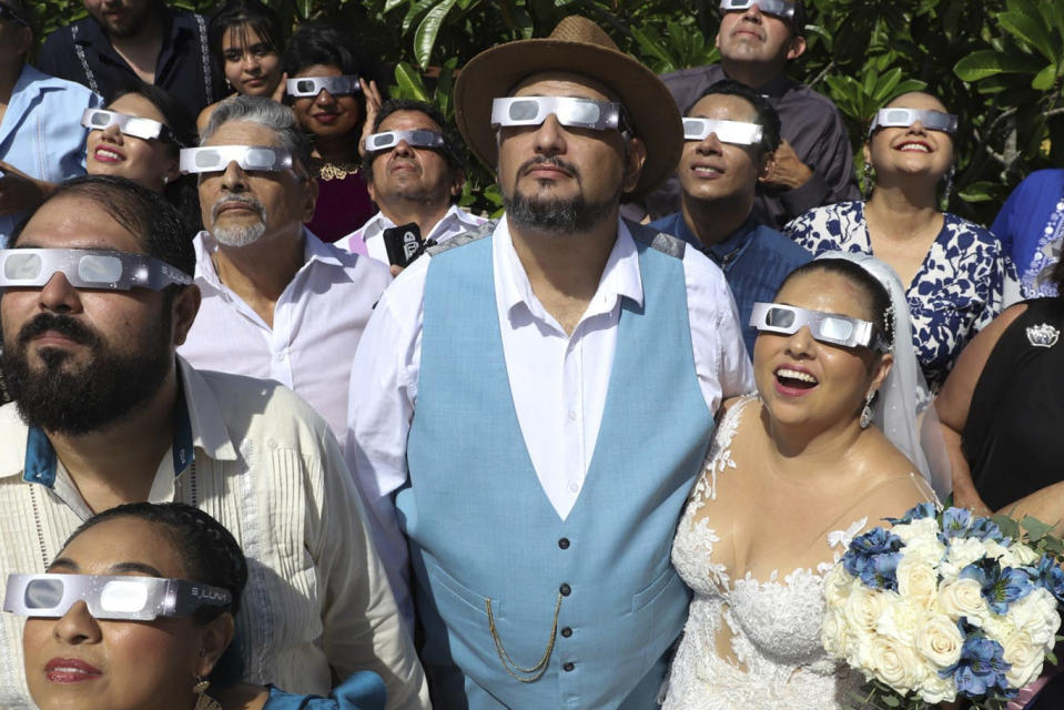 Isaac Medina and Jazmin Gonzalez, center, watch a "ring of fire" solar eclipse before their wedding ceremony in Merida, Mexico, Saturday, Oct. 14, 2023. The annular eclipse dimmed the skies over parts of the western U.S. and Central and South America. (AP Photo/Martin Zetina)