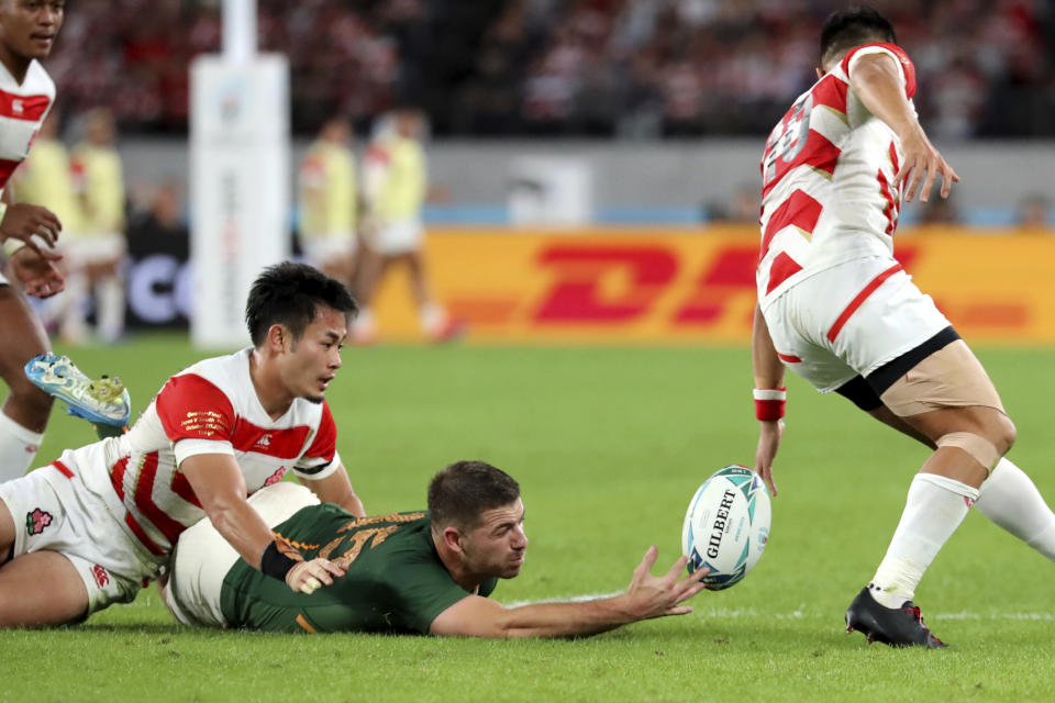 South Africa's Willie Le Roux, center, and Japan's Yu Tamura, right, vie for the ball during the Rugby World Cup quarterfinal match at Tokyo Stadium in Tokyo, Japan, Sunday, Oct. 20, 2019. (AP Photo/Eugene Hoshiko)