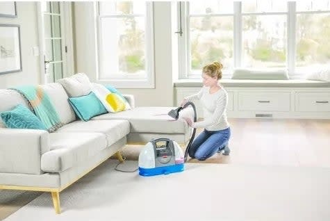 Model uses a shampooer to clean a couch