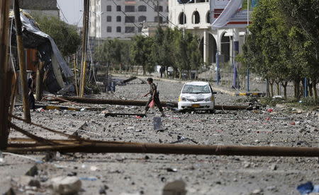 A police trooper walks on a street littered with debris by an air strike on a nearby Scud missile base in Yemen's capital Sanaa April 20, 2015. REUTERS/Khaled Abdullah