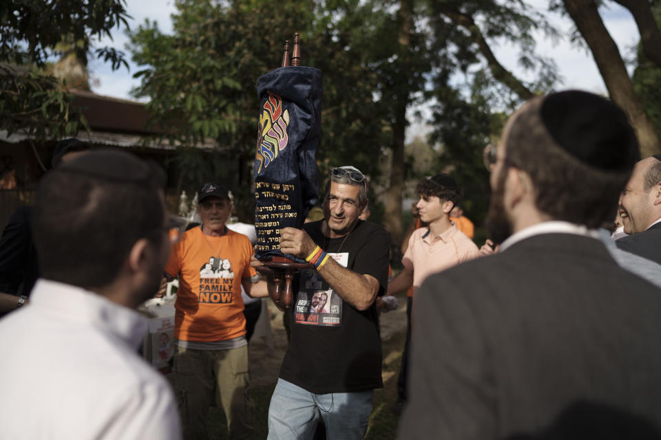 Eli Bibas holds a Torah scroll that survived the Holocaust during a ceremony marking the donation of it to Kibbutz Nir Oz, southern Israel, Wednesday, Dec. 20, 2023. Eli's son, Yarden, and daughter-in-law were kidnapped from their home in the kibbutz with their two sons, ages 4 and 10 months old, on Oct. 7, when Hamas militants crossed the border and abducted about 240 people and dragged them to Gaza. With the help of Am Yisrael Together, the Torah was donated by the Hoschander family of New York on behalf of the Hebrew Academy of Long Beach to show support for the community. (AP Photo/Leo Correa)