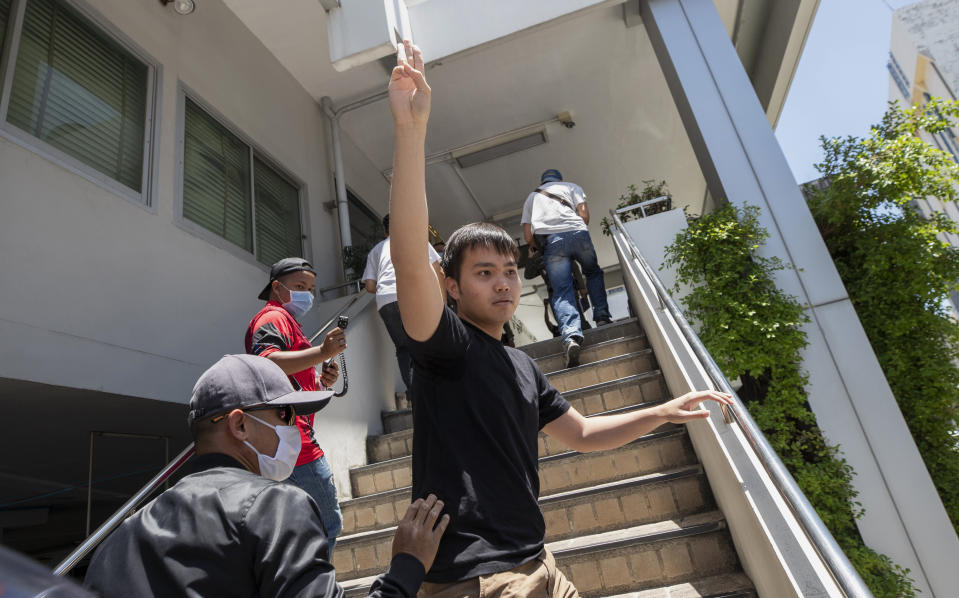 Tattep Ruangprapaikitseree raises a three-finger salute, a symbol of resistance, as he arrives at the Samranrat police station in Bangkok, Thailand, Wednesday, Aug, 26, 2020. He's among the leaders of a student movement organizing protests to demand that the government of Prime Minister Prayuth Chan-ocha call new elections, the constitution be amended to be more democratic and harassment of critics of the government cease. The police have arrested several other members of the movement on various charges, including sedition. (AP Photo/Sakchai Lalit)