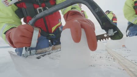 A scientist from the U.S.-led Northwest Passage Project saws an ice core drilled from the Canadian Arctic during an 18-day icebreaker expedition that took place in July and August 2019