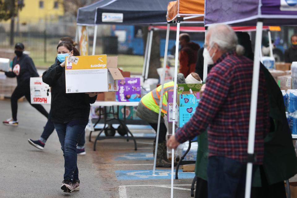 Workers help to dispense food, water and hygiene products to people in need at the Millennium Entertainment Center food distribution site in East Austin on Thursday, Feb. 25, 2021. 