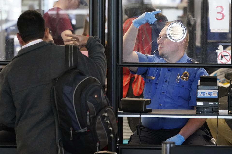 FILE - A Transportation Security Administration agent signals for the next airline passenger in line at a security checkpoint in Chicago's O'Hare International Airport Friday, May 26, 2023. On Aug. 25, The Associated Press reported on stories circulating online incorrectly claiming TSA managers were told on Aug. 15 that by mid-September they, along with airport employees, will again be required to wear face masks and by mid-October the policy will apply to travelers as well. (AP Photo/Charles Rex Arbogast, File)