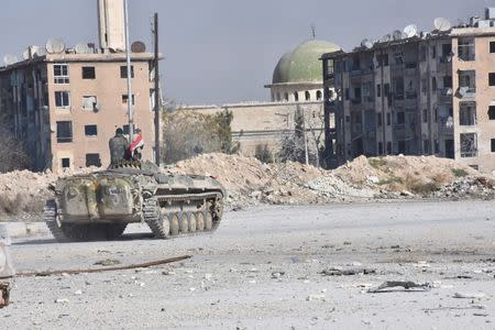 A Syrian government soldier rides a military vehicle near a mosque, after taking control of Aleppo's Al-Haidariya neighbourhood, Syria in this handout picture provided by SANA on November 28, 2016. SANA/Handout via REUTERS