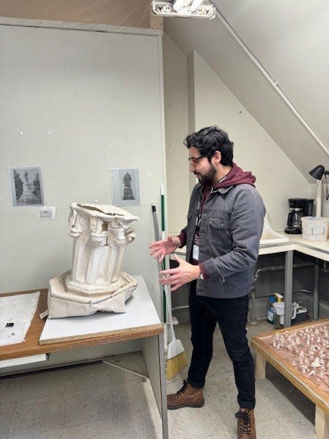 Pratt Munson artist-in-residence Felipe Lopez stands with a component of his piece "Consagrado a la memoria" or "Dedicated to memory," explaining how the hemp paper pedestal sags and leans over time.