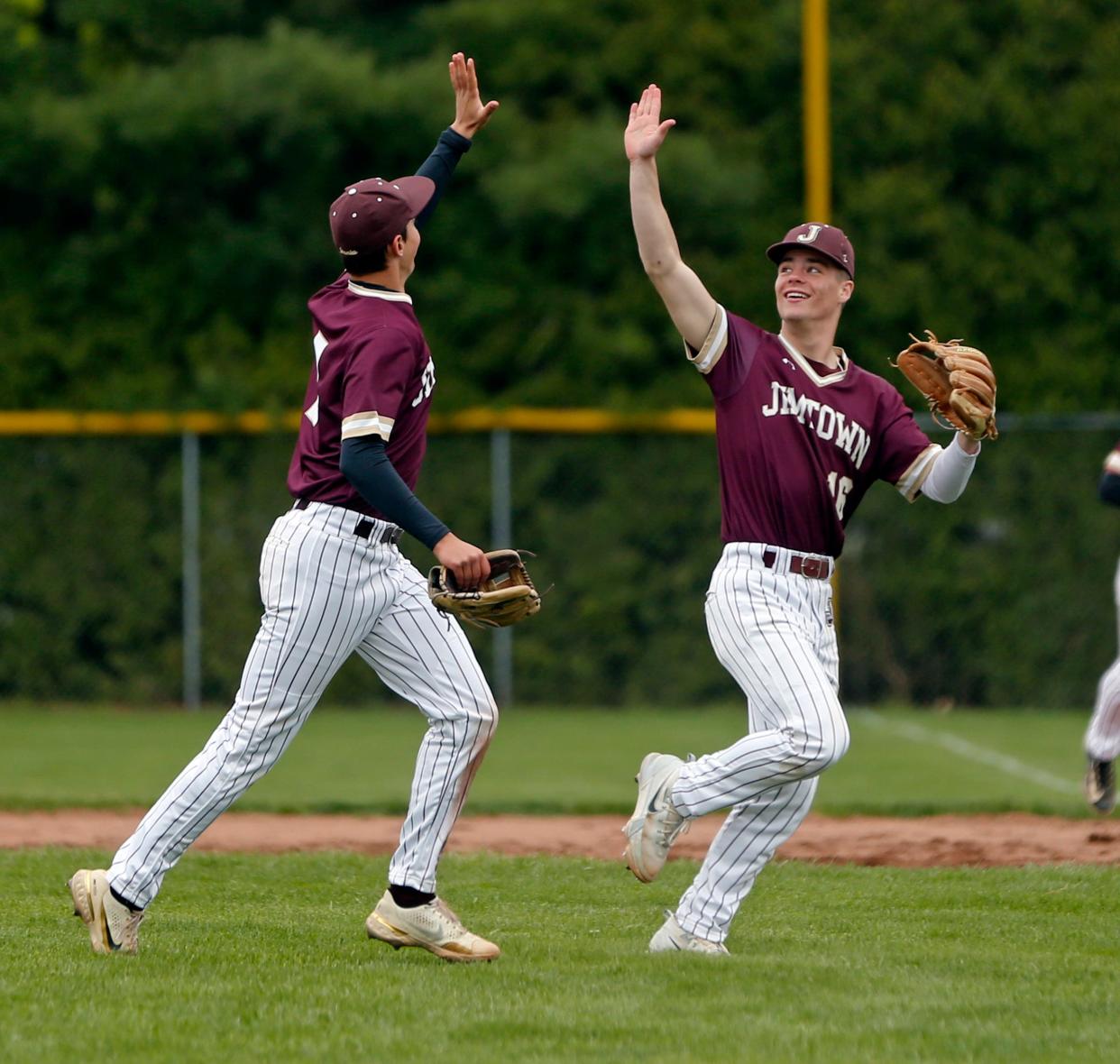 Jimtown junior Connor Christman (16) and sophomore Dalton Cook go to high-five each other after the ending of the second inning during a baseball game against Bremen Wednesday, April 24, 2024, at Bremen High School.