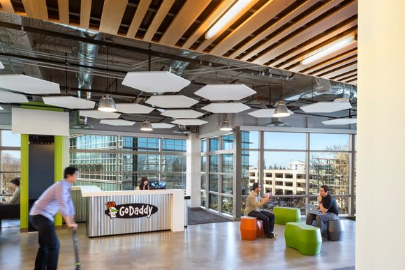 Employees sitting on colorful seats and riding a scooter at GoDaddy headquarters.