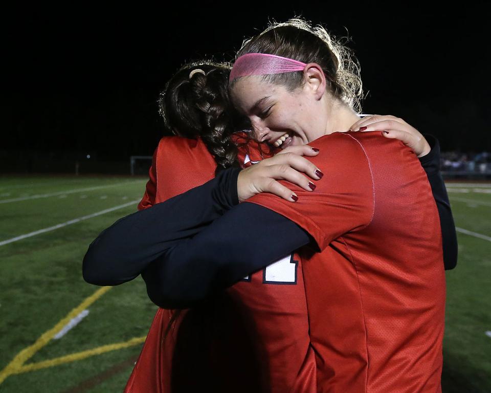 Hingham's Claire Murray and Hingham's Bridgette Harrington hug Hingham's Ava Varholak after her penalty kick won the Division 1 state semifinal game against Bishop Feehan at Whitman Hanson High School on Tuesday, Nov. 15, 2022. Hingham won on penalties 4-3 after ending the game 1-1 in double OT.