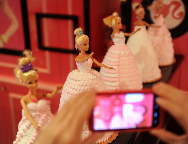 A Barbie fan takes pictures of cakes during the opening ceremony of a Barbie-themed restaurant in Taipei on January 30, 2013. "We picked Taiwan because theme restaurants are very popular and successful here. We are very confident that the Barbie Cafe can promote our brand image," said Iggy Yip, a senior manager in Mattel's consumer products division in Greater China