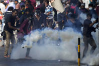 Students run for cover as police fire tear gas to disperse protesting members of the Inter University Students Federation during an anti government protest in Colombo, Sri Lanka, Thursday, May 19, 2022. Sri Lankans have been protesting for more than a month demanding the resignation of President Gotabaya Rajapaksa, holding him responsible for the country's worst economic crisis in recent memory. (AP Photo/Eranga Jayawardena)