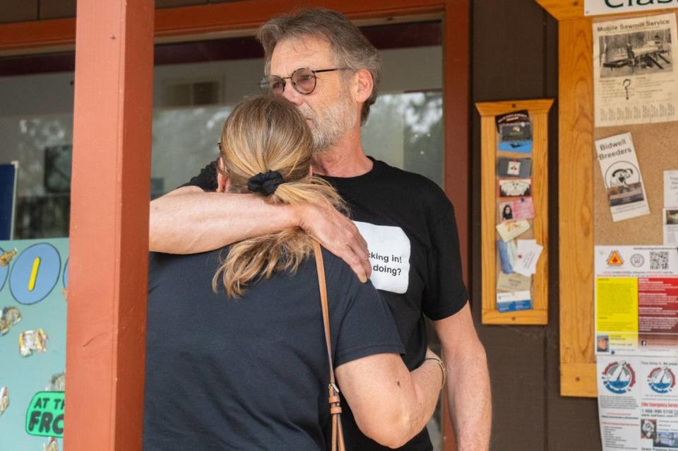 Dennis Fischer, back, comforts his wife Linda Fischer in front of the Forest Ranch Post Office on Wednesday. The Fischers went into town to get their mail before meeting a contractor at their home, which had been destroyed in the Park Fire.