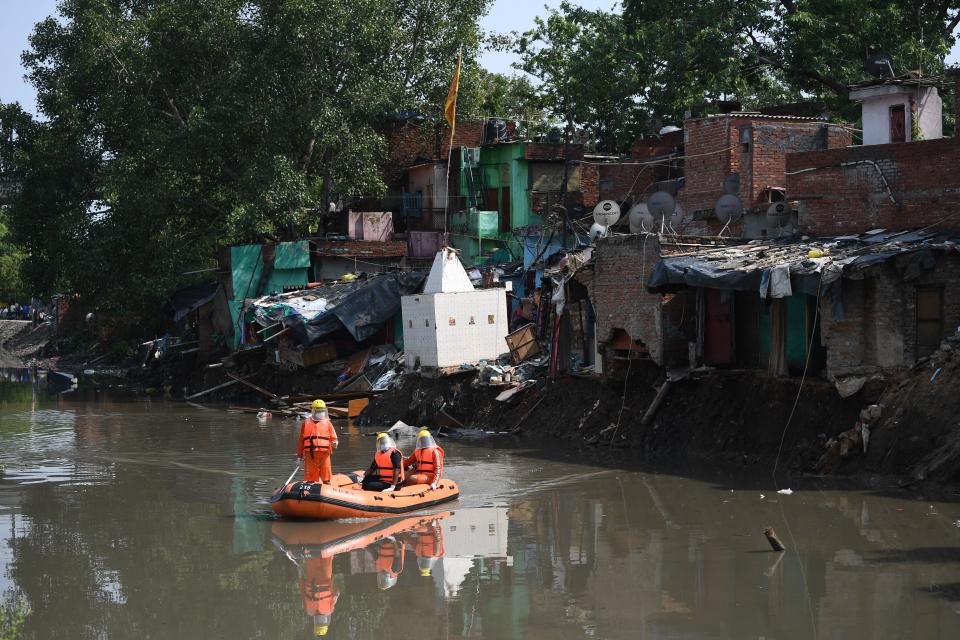 National Disaster Response Force personnel inspect on a dinghy the area where some shanty houses collapsed into a canal due to heavy rains in New Delhi on July 19, 2020. (Photo by Sajjad HUSSAIN / AFP) (Photo by SAJJAD HUSSAIN/AFP via Getty Images)